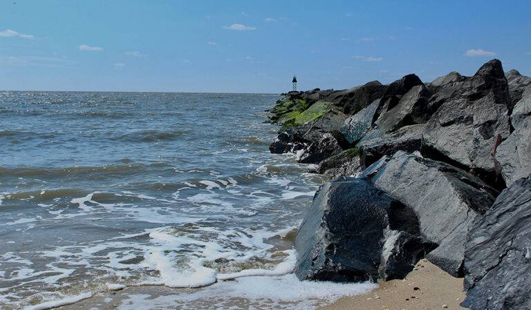 "Scenic view of Higbee Beach, with waves crashing on the shore under a clear blue sky."