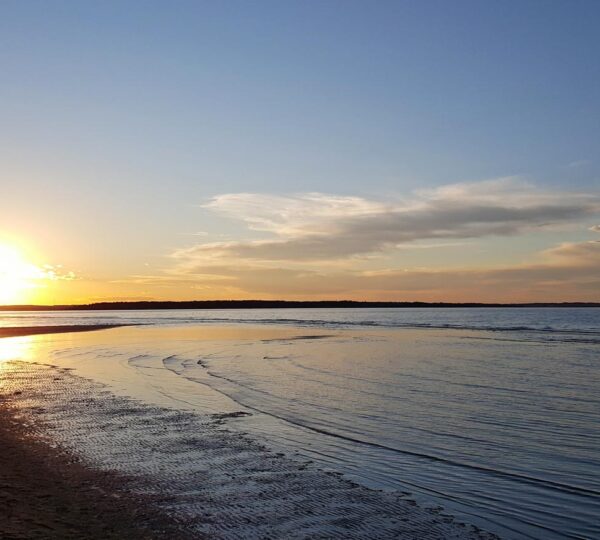 Sandy shoreline with calm waves and blue sky at Parlee Beach.